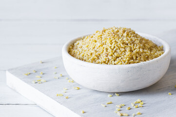 Dry bulgur wheat grains in bowl or spoon on table. Heap of uncooked bulghur , cereal food
