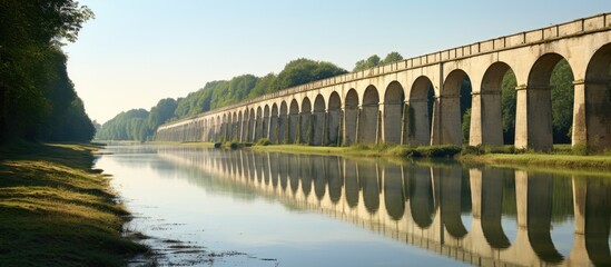 Majestic Stone Bridge Spanning Over Calm Waters in a Serene Natural Landscape - obrazy, fototapety, plakaty