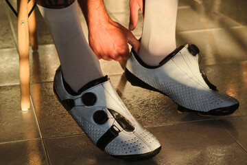 A male cyclist is putting on cycling shoes. Bicycle shoes with a modern system of tightening the boa. 