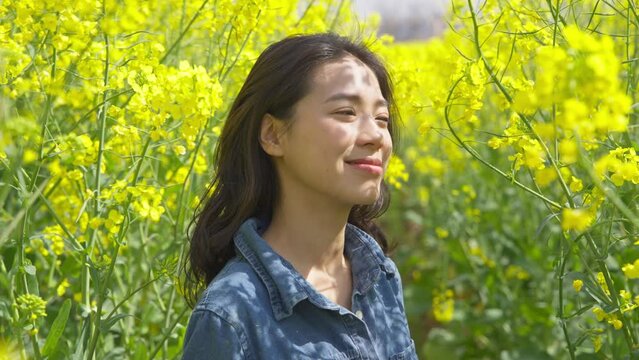 pretty young asian woman enjoy the spring sunny day at rapeseed flower field