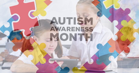 Image of autism awareness month text over diverse schoolchildren using tablet - obrazy, fototapety, plakaty