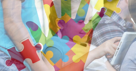 Image of puzzle pieces and hand over diverse schoolchildren using tablet