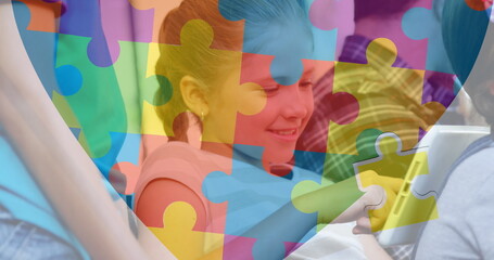 Image of puzzle pieces over diverse schoolchildren using tablet