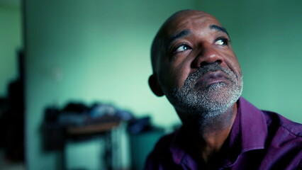 One hopeful senior black man seeking faith during challenging times, close-up face of 50s person of...