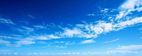 A beautiful blue ocean with a few clouds in the sky. The sky is clear and the water is calm