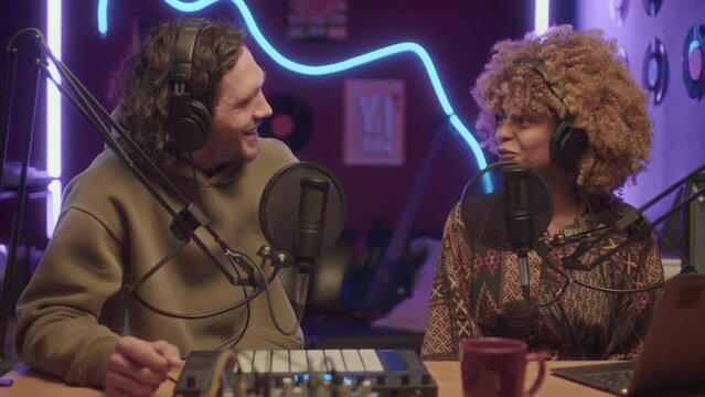 UGC footage of cheerful diverse friends hosting online show recording it at home studio with neon string lights at night
