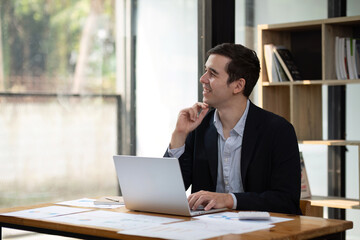 Fototapeta premium Businessman working on laptop Data analyst and creative designer Look at the camera and smile. A digital entrepreneur works on an e-commerce startup.