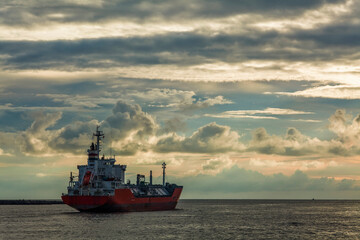 At sunset, the sun is about to enter the sea, and a ship is sailing on the sea.