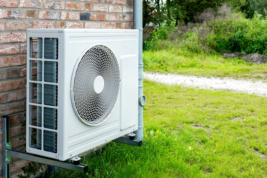 Heat pump, sustainable heating solution for modern homes. Environmentally Friendly Heat Pump Technology in Front of a brick house.