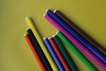 Fototapeta premium Colored markers on a yellow background. A set of colored pencils. Tools for drawing. Training of fine motor skills. A set for creativity. Space for writing