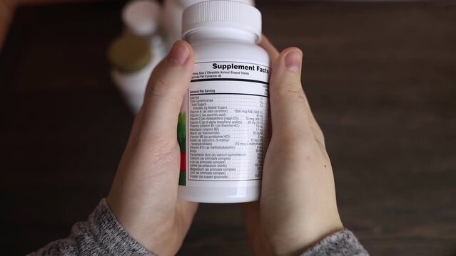 Girl studies dietary supplements. Reading the instructions on a bottle of vitamin complex. Nutritional supplement for hair loss and  weakened immunity. Self-prescription of drugs and harm to health	