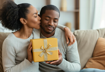 Joyful Embrace: African American Couple Sharing a Heartfelt Moment with a Festive Gift - obrazy, fototapety, plakaty