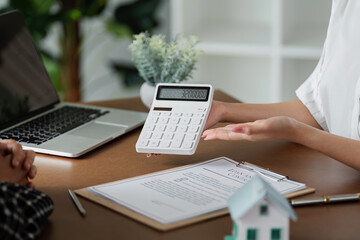 Real estate agent holding calculator and showing about property tax to client