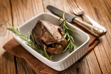 roasted pigeon with herbs over wood background