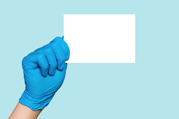 doctor hand in protective latex blue nitrile medical glove holding blank card. Empty white...