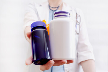 Close-up of bottles with pills in hand of female doctor. pharmacist shows bottles of medicine