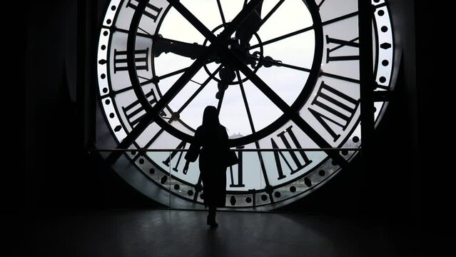 Woman silhouette standing in front of large clock, Paris, France. Unrecognizable person overlooking Paris.