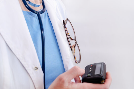 cropped image of female doctor reading a text message on pager. Calling a doctor on pager, close-up