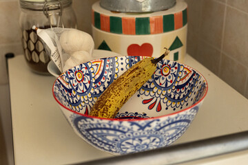 Bunch of Ripe Yellow Bananas inside a Hand Painted Ceramic Pottery Bowl in the Kitchen