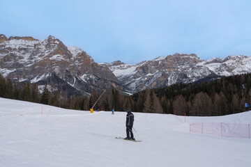 Alpine Skiers Descending a Beautiful Snowy Slope and a view of the Beautiful Surrounding Landscape of the Snow-covered of the Italian alps Dolomites Mountains.