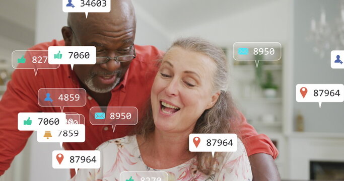 Image of social media icons and numbers over senior diverse couple at home - Powered by Adobe