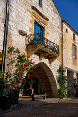 Fototapeta na wymiar Beautiful stone house with blue shutters and balcony in Monpazier, Dordogne, Nouvelle-Aquitaine
