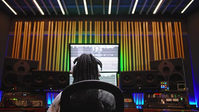 Back View of a Producer, Audio Engineer Uses Control Desk for Recording New Album Track in Music Record Studio