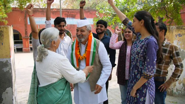 An elderly lady putting a tricolour scarf on the political party leader - elections  lok sabha party member  Indian democracy. The supporters of the political party supporting their leader for winn...