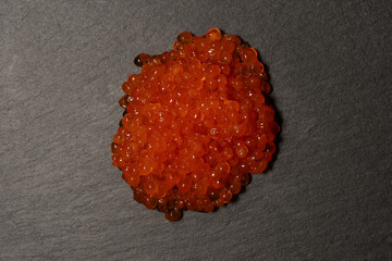 Red trout caviar on a black background.