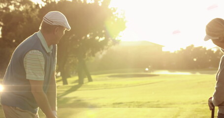 Image of light trails ver senior caucasian couple playing golf on golf course - Powered by Adobe