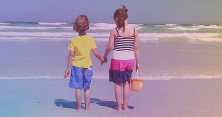 Rear view of caucasian brother and sister standing at the beach