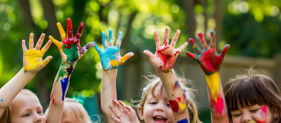 joyful children in kindergarten show their palms in paint, hands, little kids, green background, bright colors, place for text, drawing, art, paint, red, blue, schoolchildren, playground