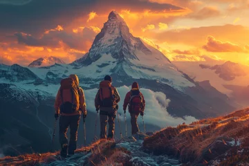 Fotobehang Three hikers approach the magnificent peak of an alpine mountain bathed in the warm glow of a fiery sunrise © Larisa AI