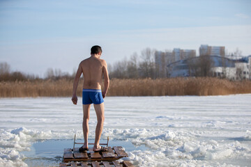 A man approaches an ice hole to plunge into the Orthodox feast of the Epiphany.
