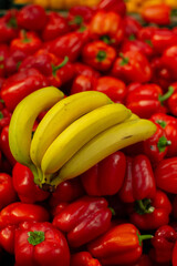 A branch of ripe bananas and peppers on the shop window.