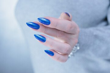 Woman's beautiful hand with long nails and bright blue manicure