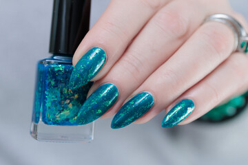Woman hand with long nails and teal blue green manicure