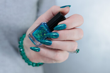 Woman hand with long nails and teal blue green manicure