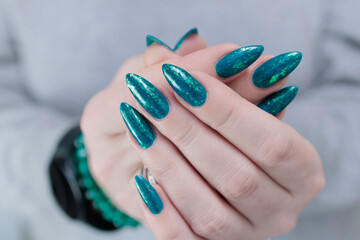 Woman hand with long nails and teal blue green manicure