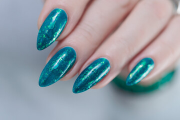 Woman hand with long nails and teal blue green manicure