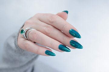 Woman hand with long nails and teal blue green manicure