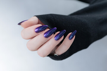 Female hands with long nails and dark purple blue manicure 