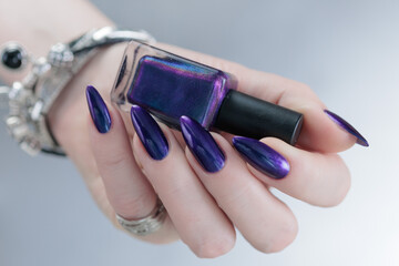 Female hands with long nails and dark purple blue manicure 
