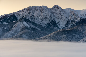 Giewont mountain, Poland Tatra Mountains in the morning with fog in the valley. Cloudless sky with sunrise colors. View from Gubalowka Mountain in Zakopane Town and Koscielisko Village. - obrazy, fototapety, plakaty