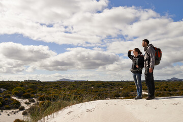 Sand dunes, nature and couple hiking for adventure, desert and travel on outdoor holiday for love...