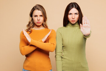 Young sad strict friend two women they wear orange green shirt casual clothes together showing stop...