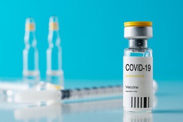 Coronavirus vaccine vial glass with a syringe on blue background. Covid-19 medicine vaccination concept. World pandemic concept.
