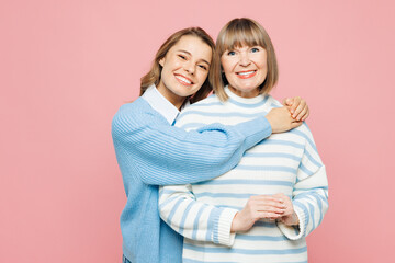 Elder smiling happy parent mom 50s years old with young adult daughter two women together wear blue casual clothes hug looking camera isolated on plain pastel light pink background Family day concept