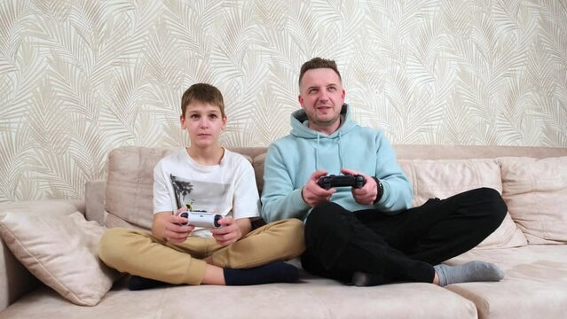 Father spends time with his little son at home and playing game console. Weekend activities, free time, home entertainment and video games concept.