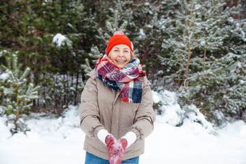 Fototapeta na wymiar Happy mature woman enjoying snowy weather in a forest